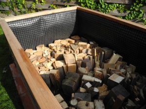 Altholz oder Scheitholz in den Hochbeetkasten einschlichten